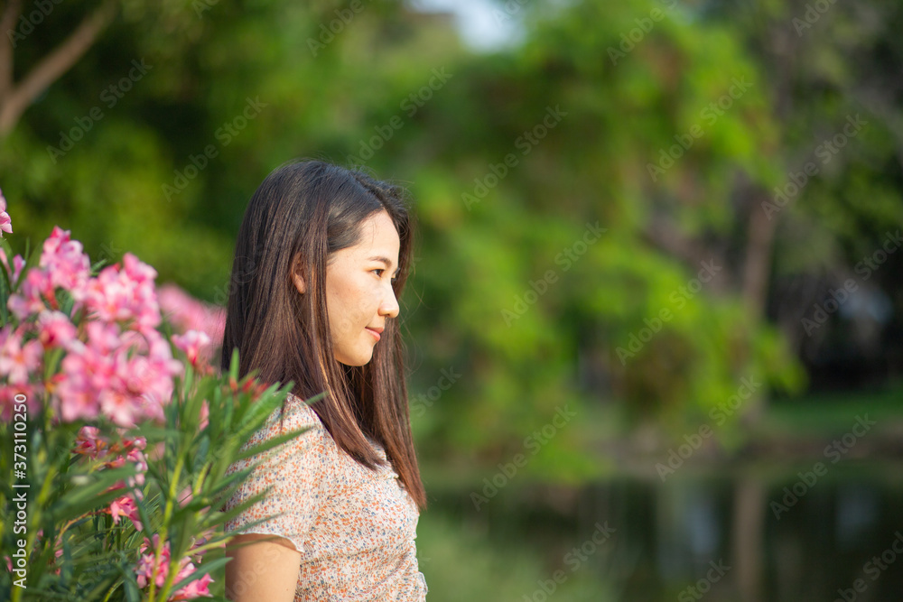 Beautiful Asian woman alone in the park with pink flowers Beautiful Asian woman alone in the park with pink flowers
