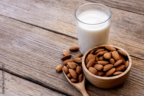 glass of milk with almonds on wood table.