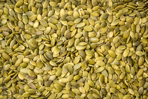 raw, organic, shelled pumpkin seeds background and texture - superfood concept