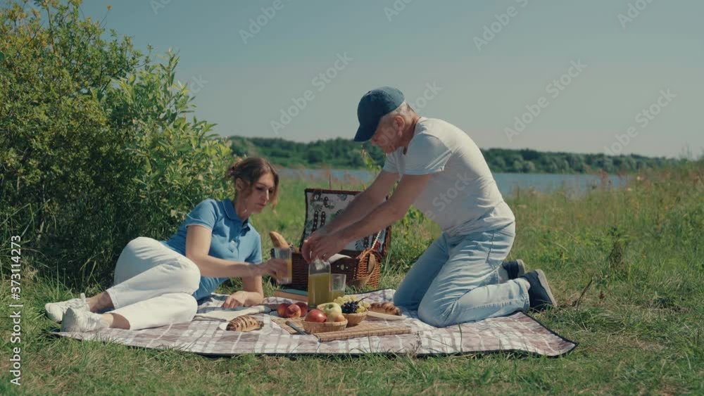 A man and a woman relax on a picnic in the summer.