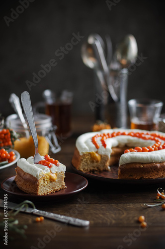 Ring pie with airy white cream and sea buckthorn. Autumn still life. Festive table setting.