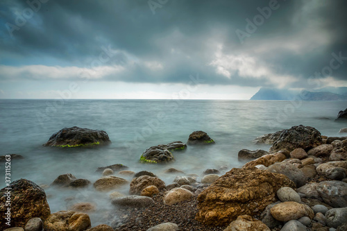 Sea beach and coastal stones in the water in the evening. Long exposure landscape.