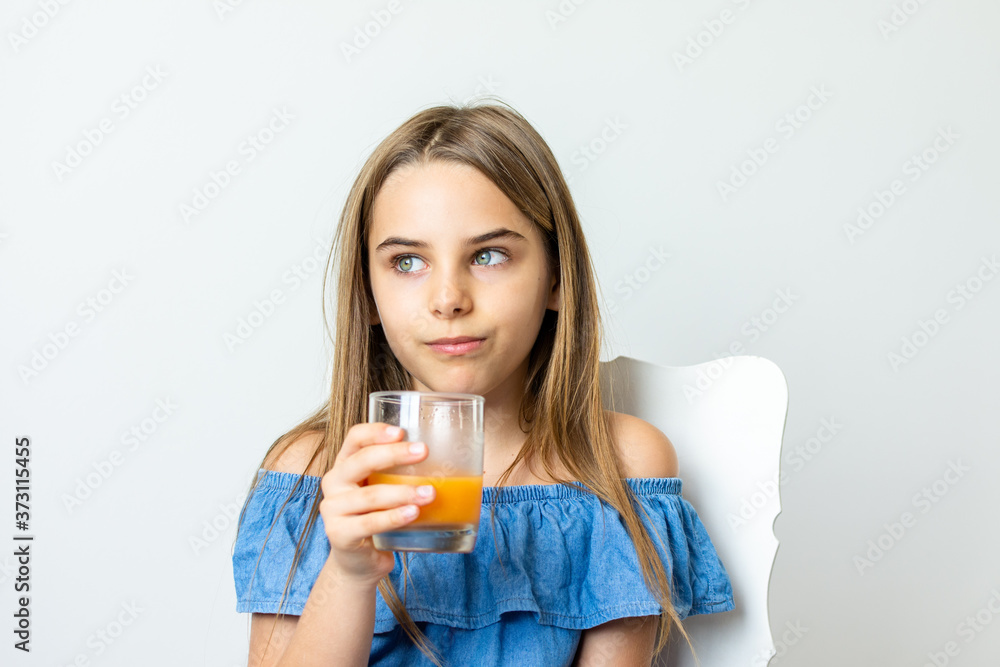 Criança menina bonita loira saboreando suco de laranja Criança menina bonita loira saboreando suco de laranja