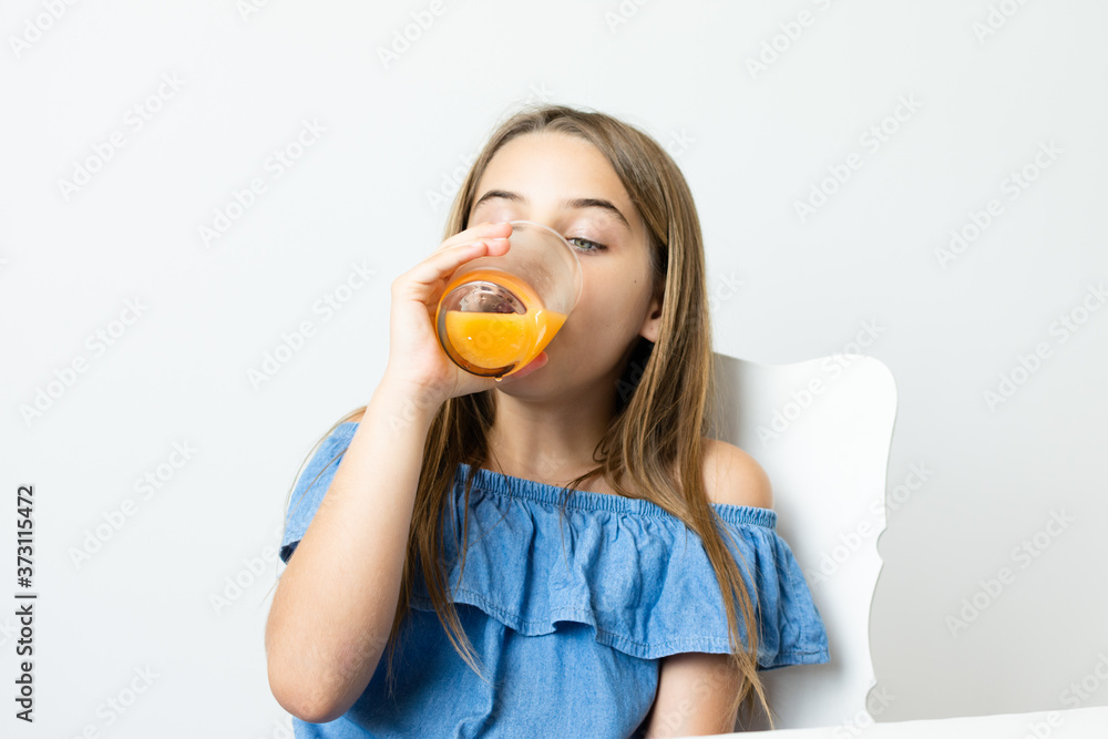 Criança menina bonita loira saboreando suco de laranja Criança menina bonita loira saboreando suco de laranja