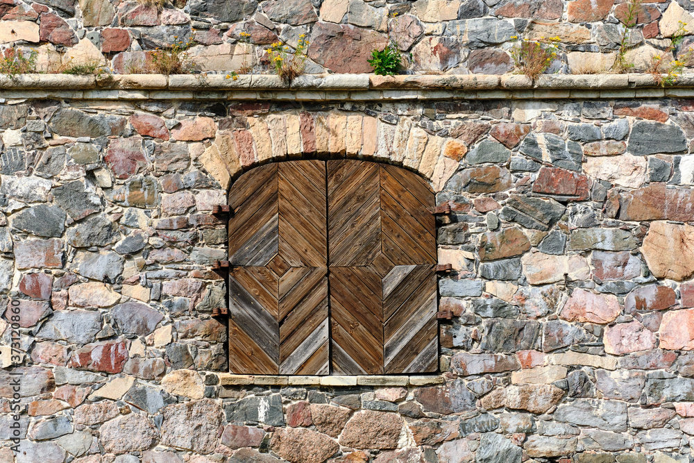 The wooden window shutters in the fortress stone wall.