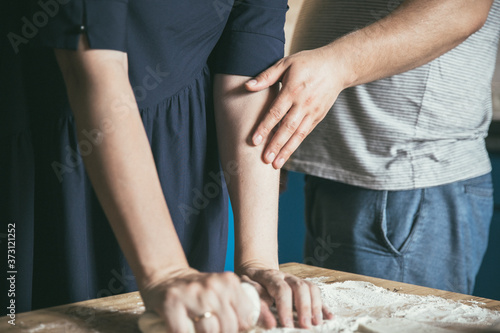 Preparing pizza dough. Young couple makes pizza for dinner. Romantic dinner. Cooking pizza at home. Rolling pin and flour on the table. Woman's and man's hands together.