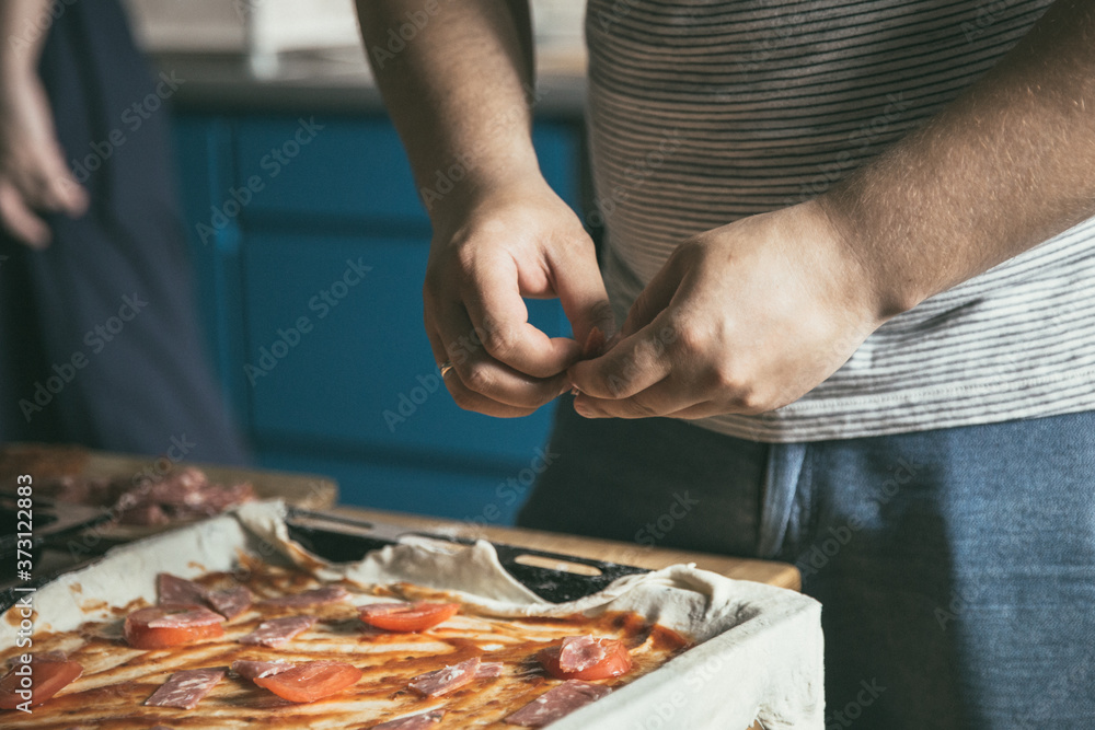 Male and female hugs in the home kitchen while cooking. Romantic kitchen in a city apartment. The lifestyle of modern youth. Young couple hugs and prepares pizza. Image with selective focus. 