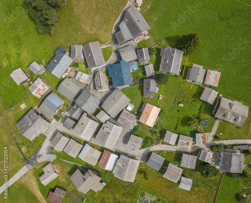 Aerial view of countryside village with small cottages in Swiss alps. Beautiful scenery with roofs from above in alpine area.