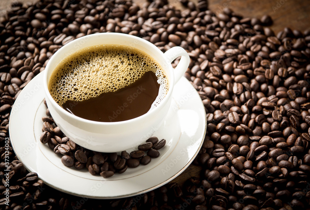cup of coffee with beans on wooden table cup of coffee with beans on wooden table