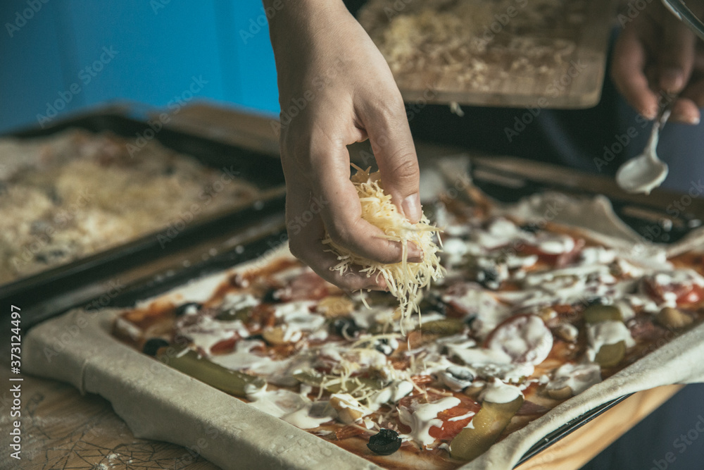 Hand with cheese. Preparing of pizza at the home. Cheese for the homemade pizza. 
Pizza time.