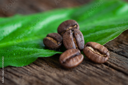 Coffee beans on a green leaf and wooden table