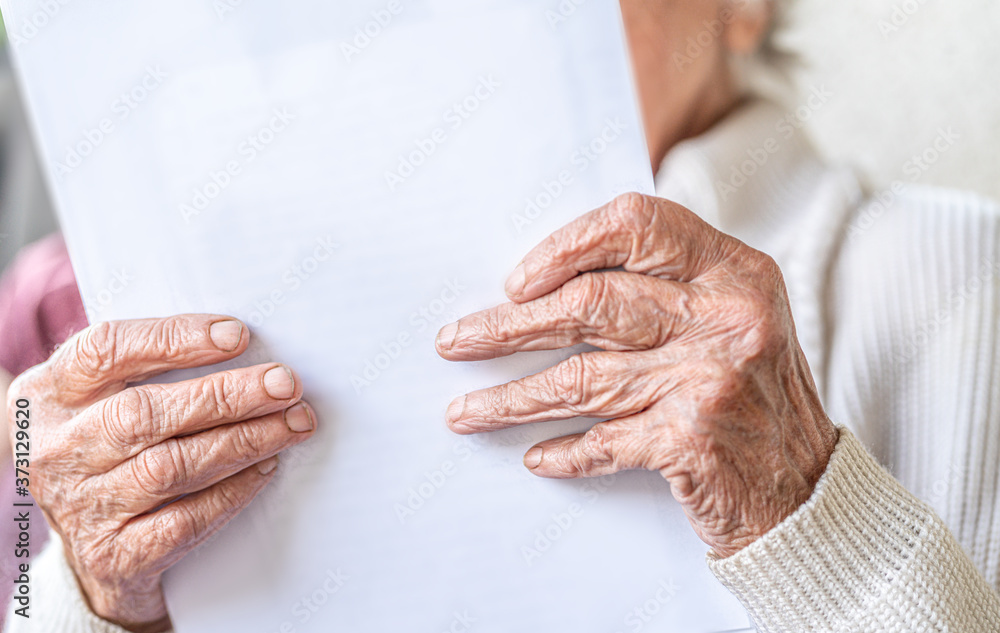 Nahaufnahme Hand, alte Frau mit faltigen Händen liest einen weißen Brief Nahaufnahme Hand, alte Frau mit faltigen Händen liest einen weißen Brief
