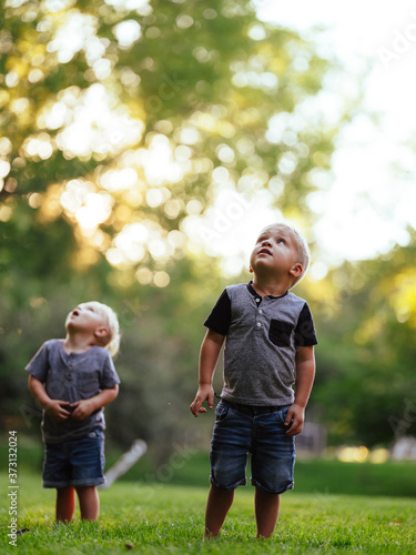 Foto Two young boys look up to the summer sky sunset in the backyard
