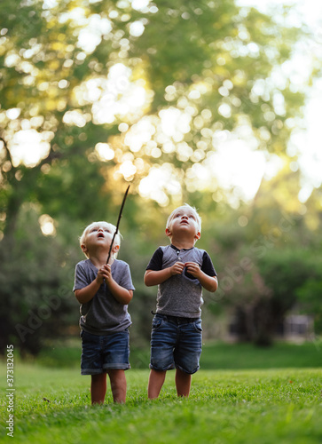 Two young boys look up to the summer sky sunset in the backyard