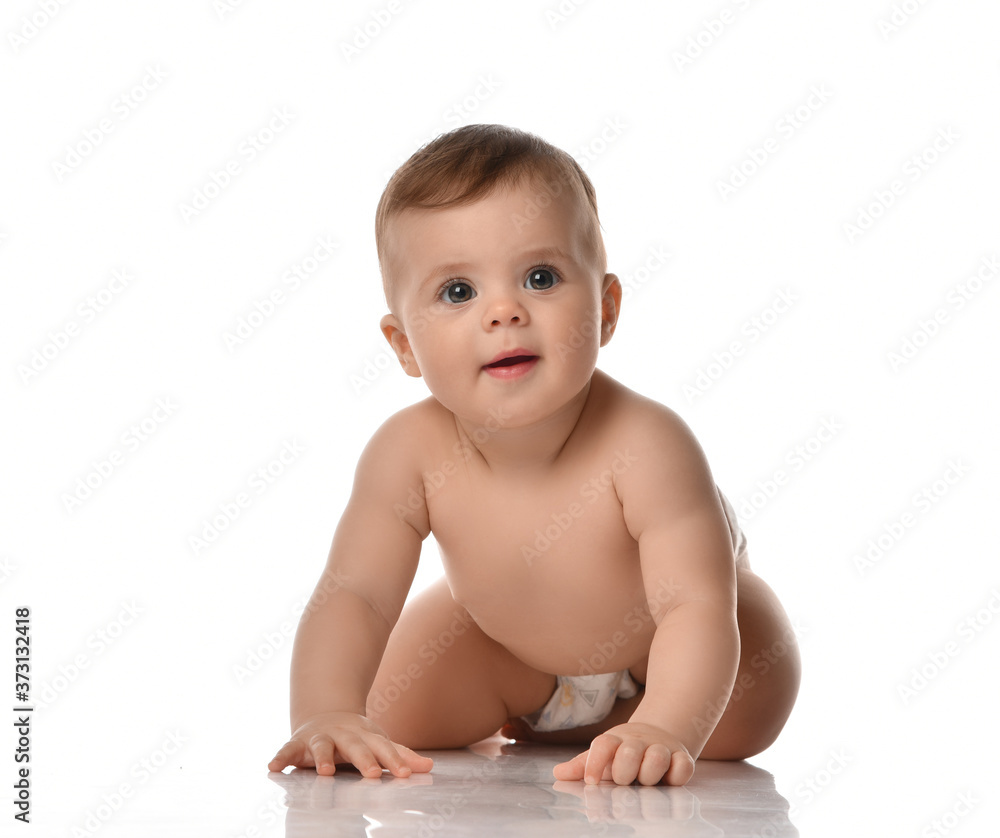 Smiling attentive infant baby toddler naked in diaper is crawling on all fours towards looking at camera Smiling attentive infant baby toddler naked in diaper is crawling on all fours towards looking at camera