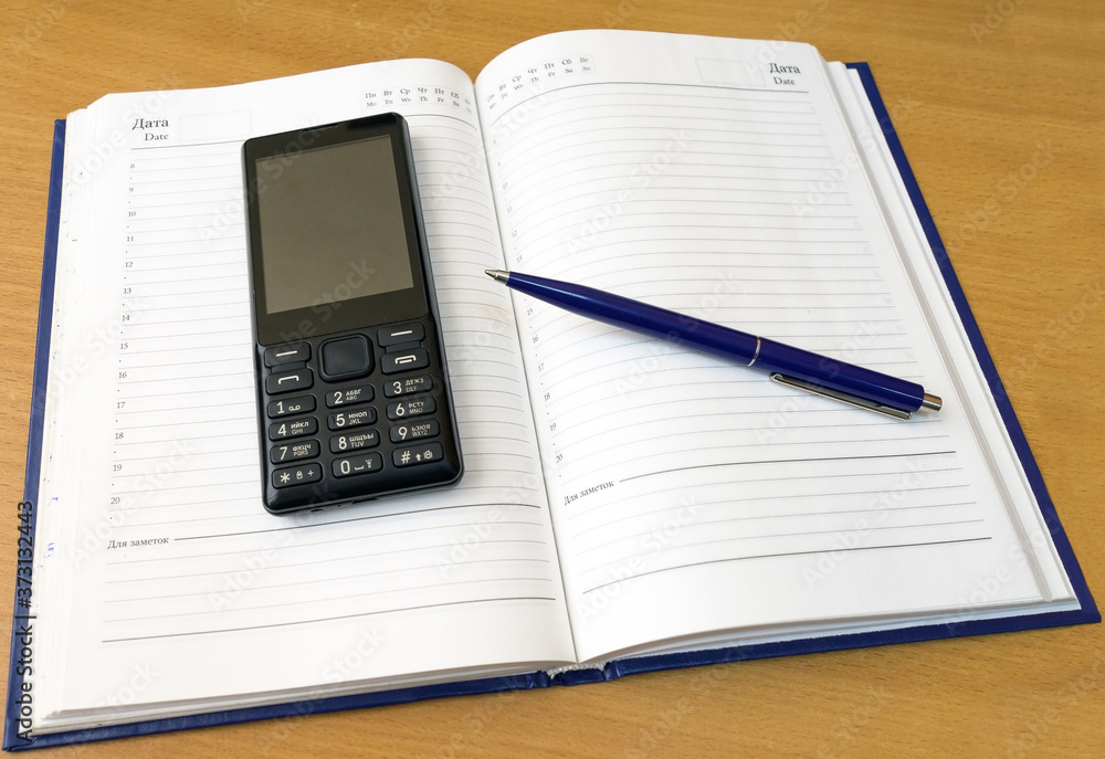 Notebook, pen and cellular telephone on desktop Notebook, pen and cellular telephone on desktop