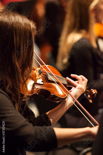 Φωτογραφία unrecognizable female brunette violinist playing in a professional orchestra