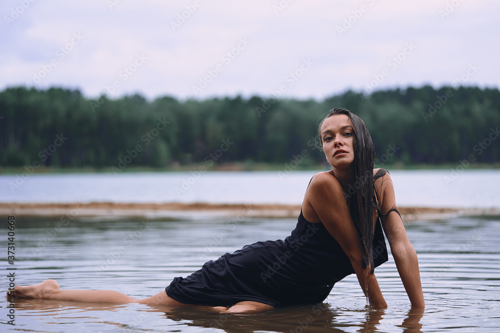 Fototapeta premium lying girl in a long black dress on the shore of the bay, the concept of the joy of health, sleep and relaxation 