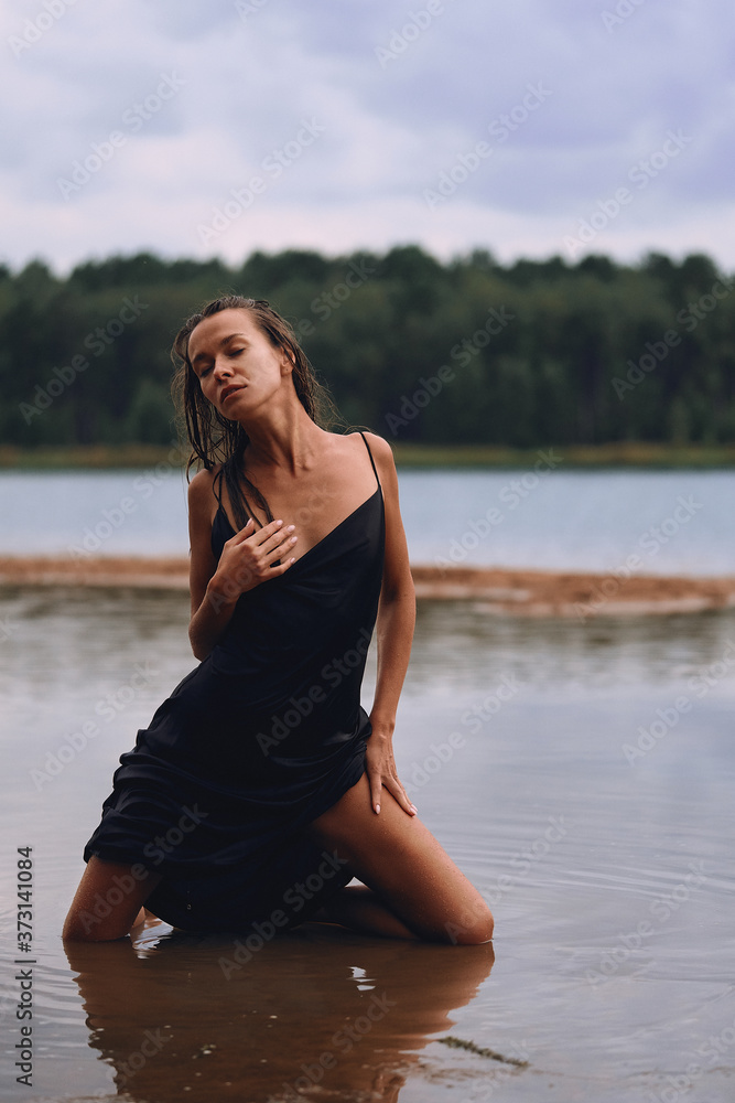 girl kneeling in a long black dress on the shore of the bay, the concept of the joy of health, sleep and relaxation girl kneeling in a long black dress on the shore of the bay, the concept of the joy of health, sleep and relaxation