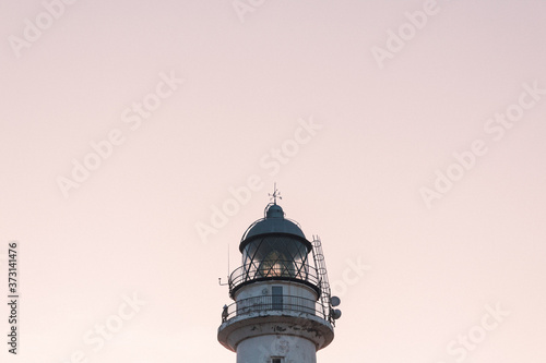 Detail of a white lighthouse at sunset in the Atlantic Ocean.
