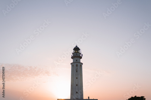 White lighthouse at sunset in the Atlantic Ocean.