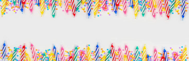 Colorful birthday cake candles with candy sprinkles. Top view banner with double border on a white background. Copy space.