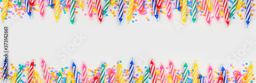 Colorful birthday cake candles with candy sprinkles. Top view banner with double border on a white background. Copy space.