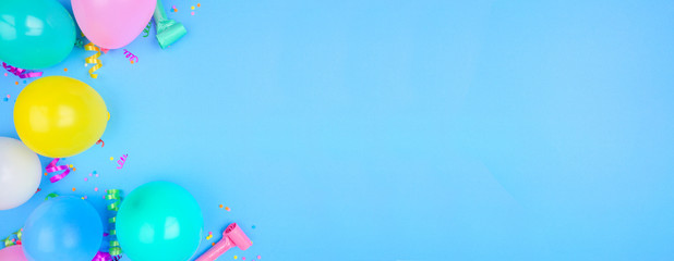 Birthday party theme banner with corner border on a blue background. Top view with balloons, streamers and confetti. Copy space.