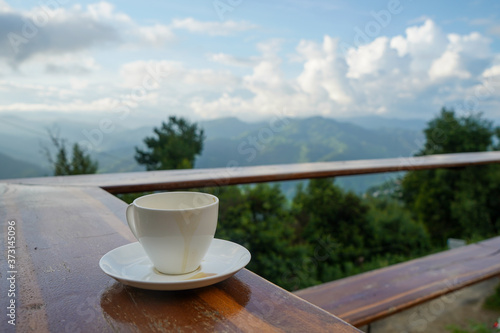 Cup with tea on table over mountains landscape with clouds. Beauty nature background