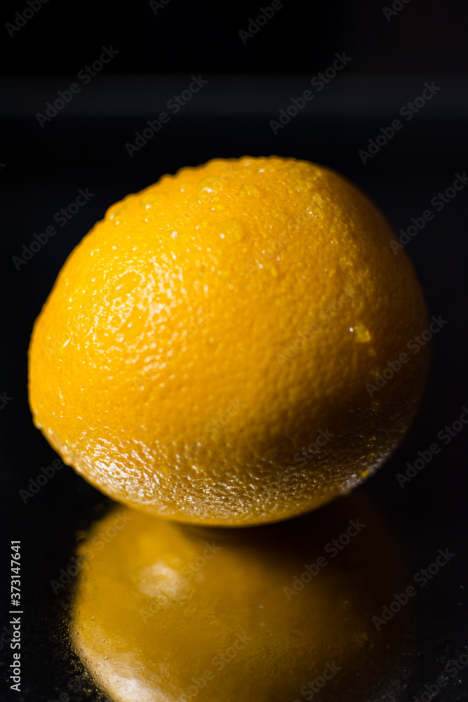 Orange orange close-up on a black background. Dew close-up on an orange.