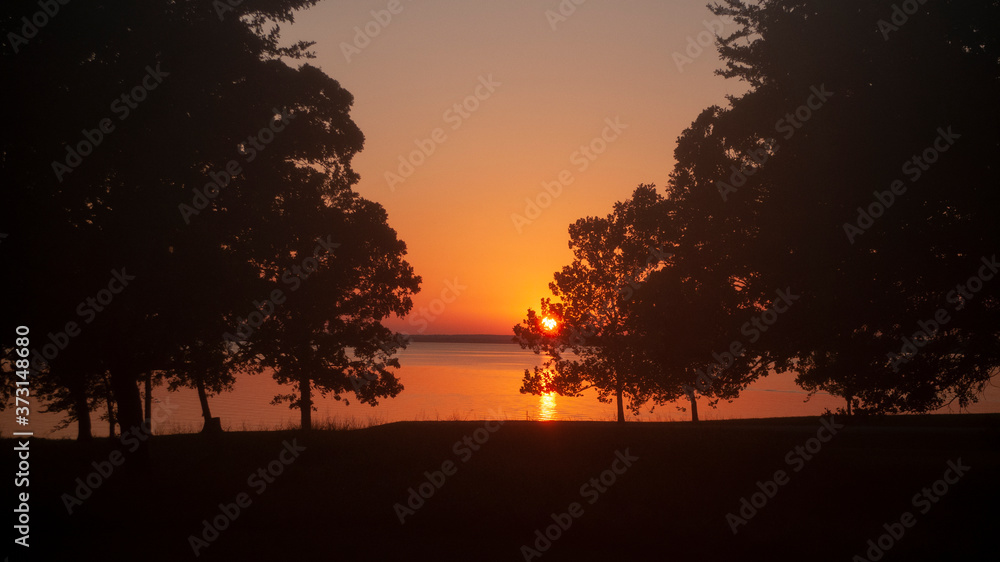 Sunset on the lake with trees in silhouette