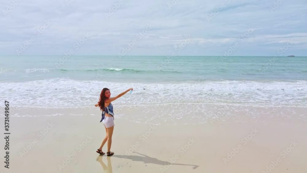 asian woman running from beach to the sea and removing medical face mask. happy female open arm taking fresh air. concept of covid19 and coronavirus ended. asian woman running from beach to the sea and removing medical face mask. happy female open arm taking fresh air. concept of covid19 and coronavirus ended.