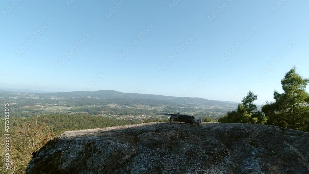 view of a drone taking off from a cliff against a blue sky, beautiful natural landscape
