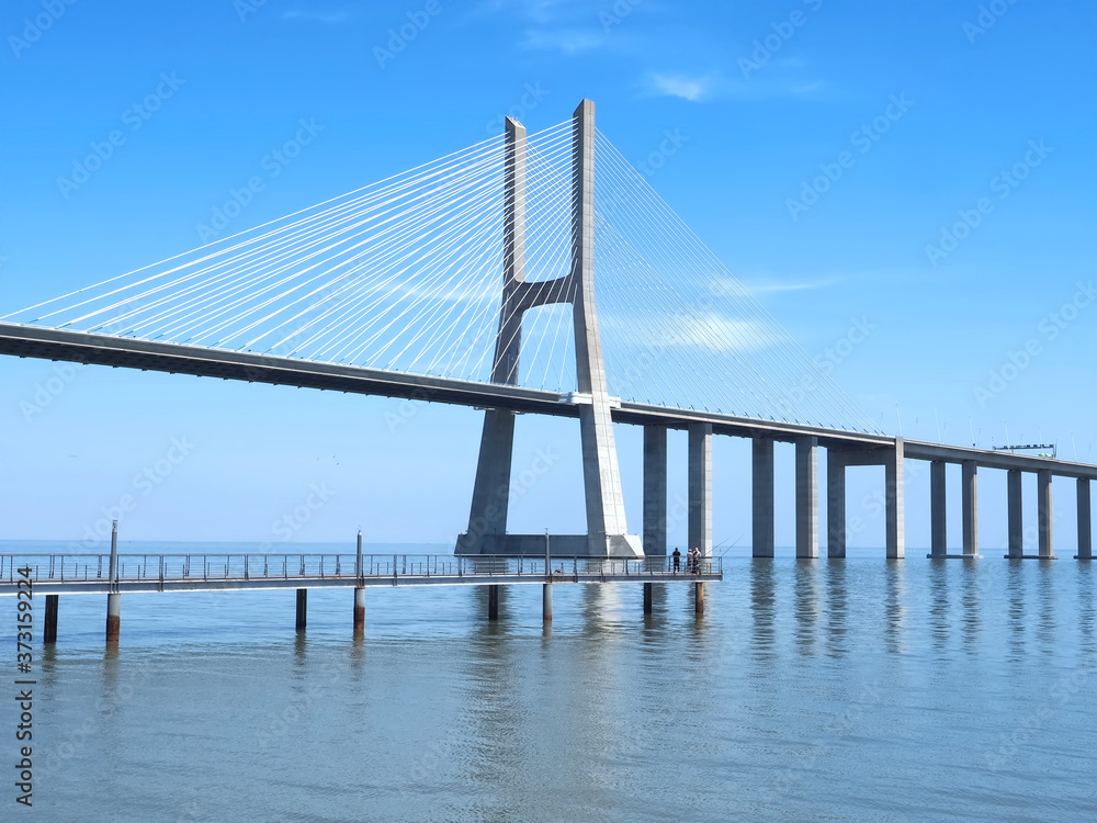 Obraz premium Walking the footpath Passeio do Tejo along Tagus river in Lisbon at the Expo park - Vasco da Gama bridge