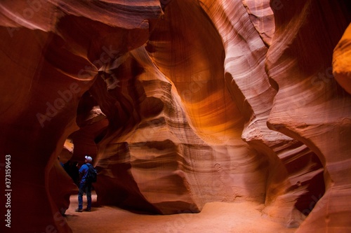 View of the inside of a slot canyon in Page, Arizona. Antelope canyon features sandstone rock formations with erosion lines throughout the walls. A person can be seen which gives perspective.