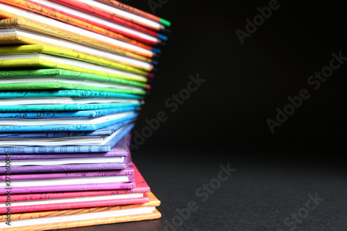 Edukacja - podręczniki w kolorowych okładkach ułożone w stos, kolory tęczy