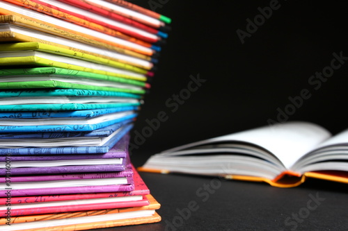 Edukacja - lektury szkolne, książki ułożone jedna na drugą w kolorach tęczy na ciemnym tle © Cezzar
