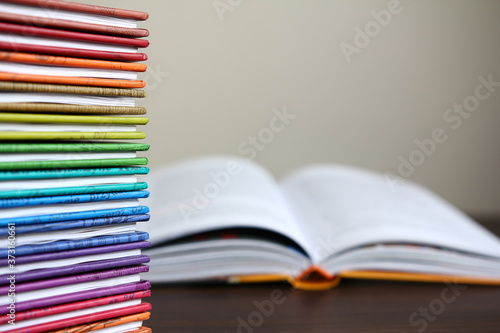 Kolorowe książki ułożone w stos, otwarta książka w tle