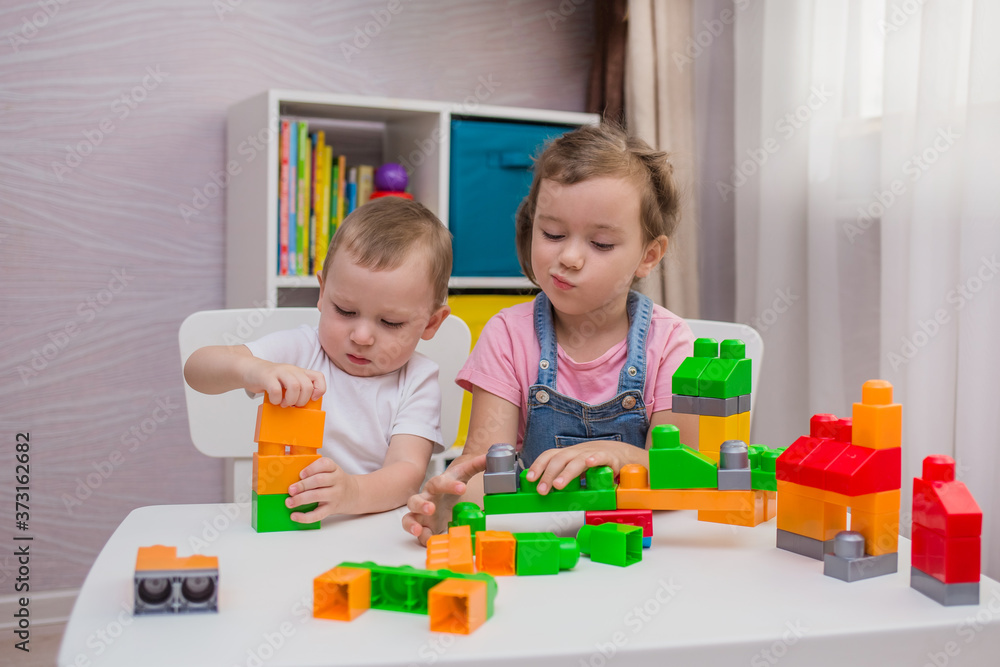 a little boy and a girl are playing a game of constructor at a table in a room a little boy and a girl are playing a game of constructor at a table in a room