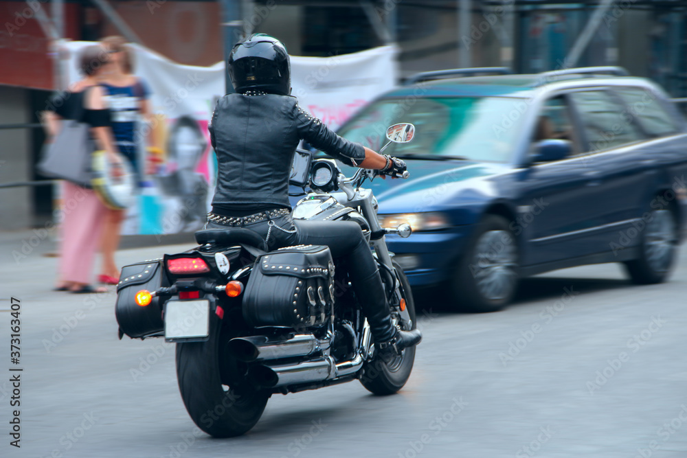 Stylish girl in black leather clothes driving on motorcycle