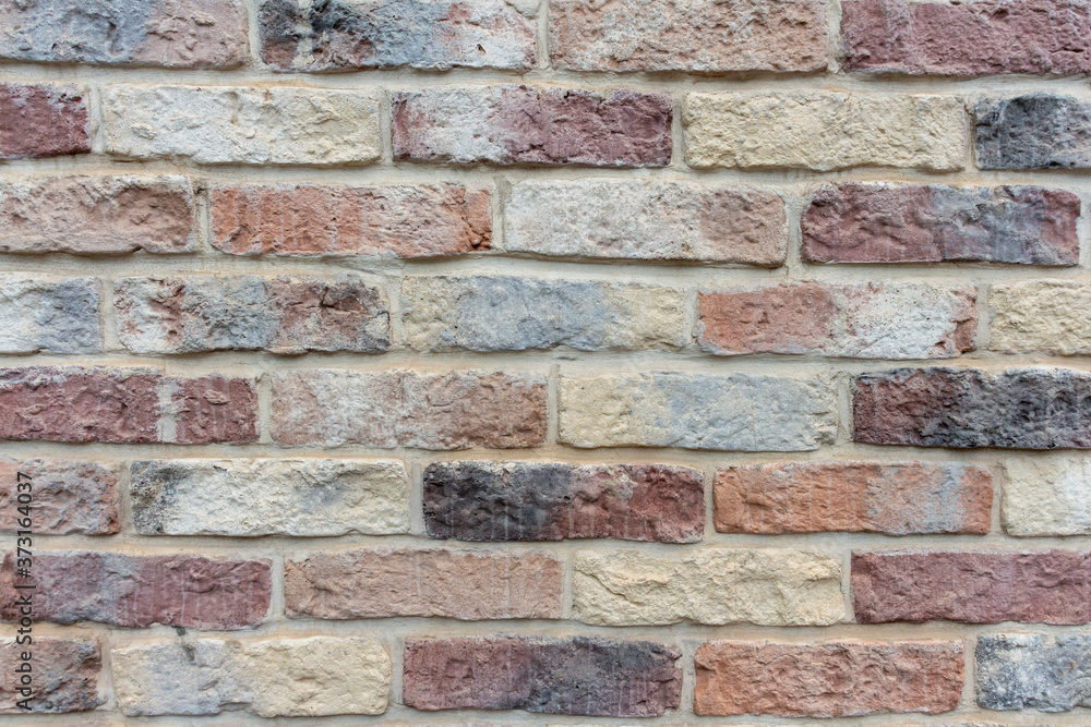 Fototapeta premium View of old shabby wall made from multicolored bricks. Abstract textured background. Copy space for your text and decorations.