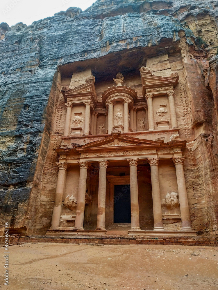 View of temple Al-Khazneh (The Treasury) carved in red sandstone rock during rain in ancient Petra city in Jordan. There is no people in front of monument. Beautiful landscape. Travel theme.