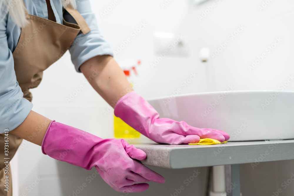 Obraz premium Housework and domestic lifestyle: woman doing chores in bathroom at home, cleaning wash basin and tap with spray detergent