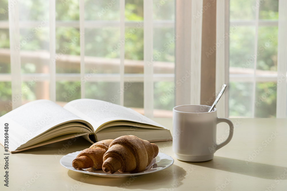 Cozy morning at home with cup of aromatic coffee, homemade hot croissants and interesting book. Cozy morning at home with cup of aromatic coffee, homemade hot croissants and interesting book.