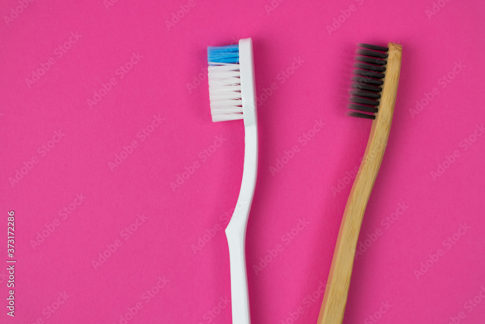Plastic Toothbrush or Bamboo Eco Toothbrush? Conscious choice. Two brushes on a pink background on the right side of the photo. Copy space Plastic Toothbrush or Bamboo Eco Toothbrush? Conscious choice. Two brushes on a pink background on the right side of the photo. Copy space