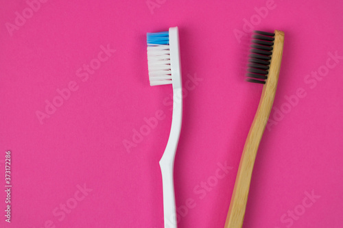 Plastic Toothbrush or Bamboo Eco Toothbrush  Conscious choice. Two brushes on a pink background on the right side of the photo. Copy space