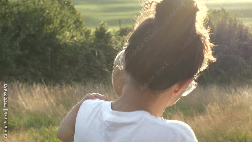 Close up mother holding her son on her hip while walking outdoors at sunset together. Family concept Close up mother holding her son on her hip while walking outdoors at sunset together. Family concept
