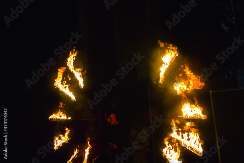 Fire show at an event in the dark. Fire show. The fakir waves fire against the explosion of firecrackers. Nightly entertainment performance great show. Fire show, dancing with flame photo