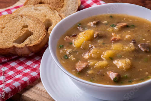 .Cassava broth. Creamy broth made with cassava, sausage, bacon and meat. .Accompanied by toast Top view Top view