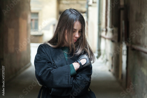 Long haired brown eyed girl in black coat portrait in a tyoicalsaint petersburg courtyard